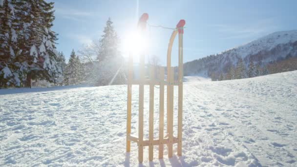 LENS FLARE: Houten slee staat recht in het midden van een besneeuwde weide. — Stockvideo