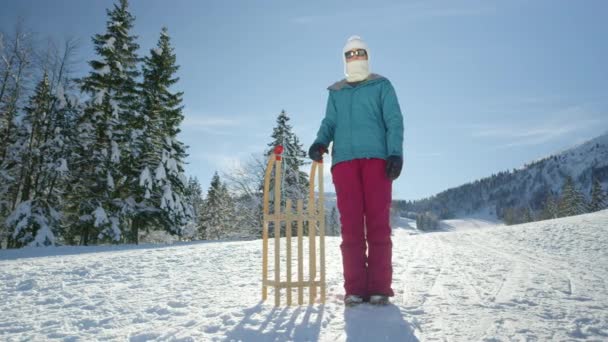 PORTRAIT: Młoda kobieta stoi obok sanek podczas dnia zabawy na Kranjskiej Górze. — Wideo stockowe