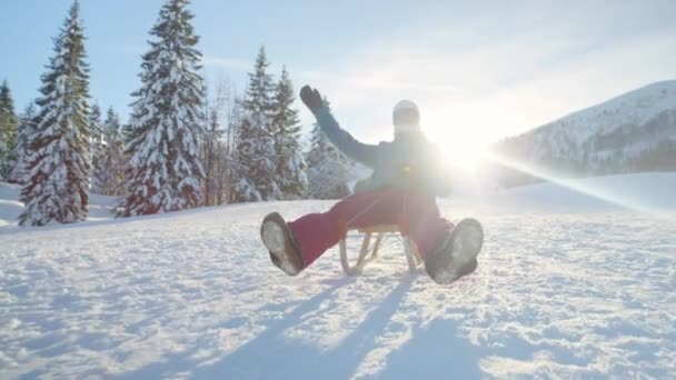 Sluiten omhoog: Jonge vrouw op actieve wintervakantie gaat sleeën op een zonnige dag. — Stockvideo