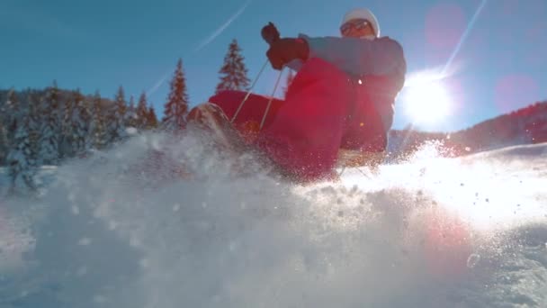 閉じる:女性が雪の丘をそりとしてカメラに輝く雪の結晶が飛ぶ. — ストック動画