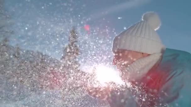 CLOSE UP, DOF: Leende ung kvinna blåser bort en handfull färska pulver snö. — Stockvideo