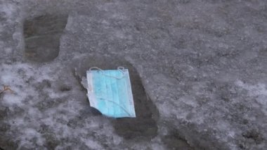 Karlı zeminde yatan bir covid-19 koruyucu maskenin detaylı görüntüsü..
