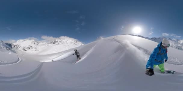 Wesoły mężczyzna spryskuje dziewczynę śniegiem podczas heliboardingu w Rockies. — Wideo stockowe