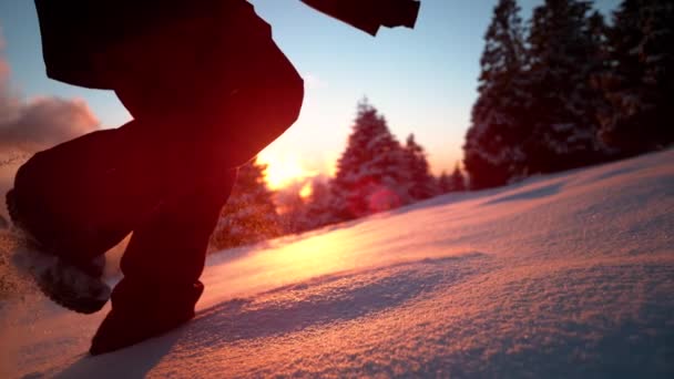 FECHAR UP: Mulher irreconhecível corre até uma colina nevada em uma noite ensolarada de inverno. — Vídeo de Stock