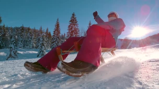 ÁNGULO BAJO: Mujer alegre de vacaciones en Kranjska Gora trineos colina abajo nevada. — Vídeo de stock