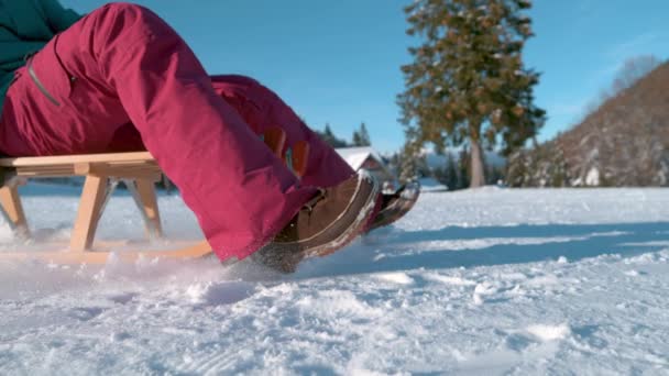 LOW ANGLE, CLOSE UP: Unerkennbare junge Frau schlittert über die verschneite Wiese. — Stockvideo