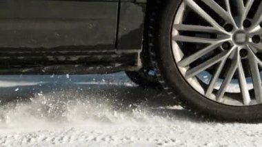 Aracın tekerlekleri yol tutuşu kazanırken kar parçaları fırlatıyor..