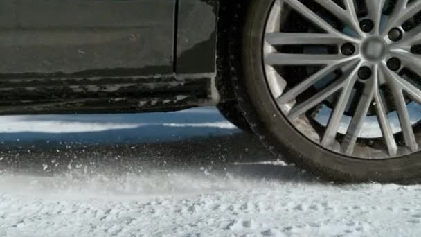 CLOSE UP: Detailed shot of car's spinning wheels as it slides along snowy road. — Stock Video