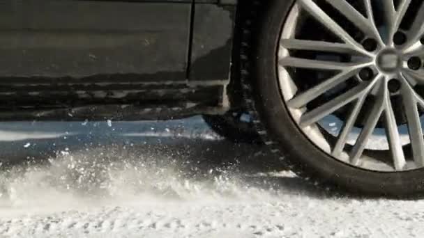 閉じる:車の車輪はトラクションを獲得しながら雪の一部を投げます. — ストック動画