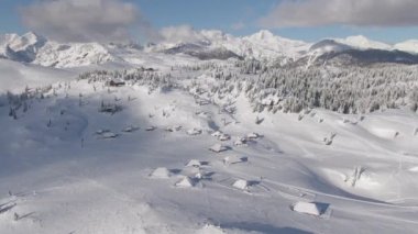 Slovenya dağlarındaki karla kaplı turizm köyünün üzerinde uçmak