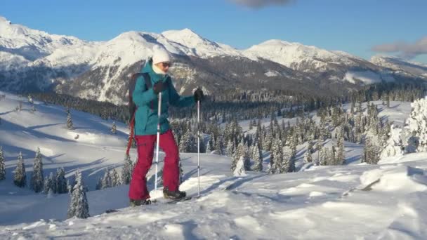 CLOSE UP: Ung kvinnlig turist på splitboarding resa vandrar uppför en snöig kulle. — Stockvideo