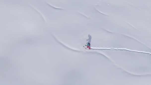 DRONE: Scenic drone shot van winterse landschap rond een vrouwelijke ski tourer. — Stockvideo