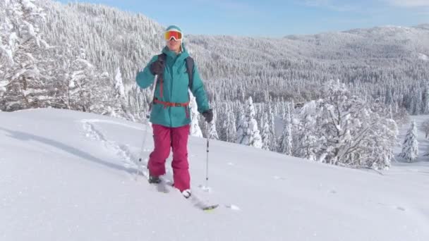 CLOSE UP: Kvinnliga turist skidåkning i Julian Alperna vandrar uppför en snöig kulle. — Stockvideo