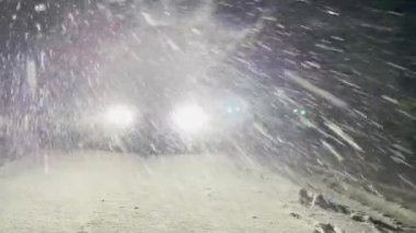 Spor arabasının parlak LED farları bir kış gecesinde karlı yolu aydınlatır.