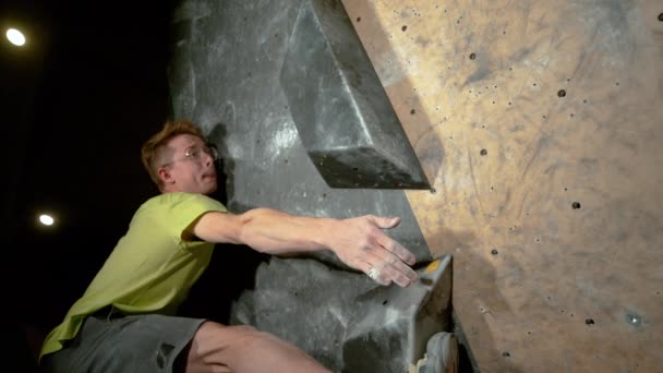 FERMER : Un jeune homme athlétique saisit une prise de volume noire en grimpant à l'intérieur. — Video