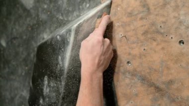 Dağcı, siyah bir hacim tutucusundaki tebeşir tozunu temizlemek için fırça kullanıyor..
