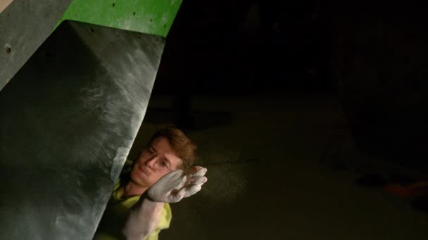 CLOSE UP: Strong man bouldering indoors firmly grips the edge of a volume hold. — Stock Video