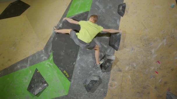 SLOW MOTION: Fit guy is boulderen op een lege sportschool vol kleurrijke muren. — Stockvideo