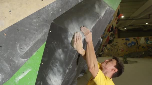 FECHAR UP: Jovem alpinista caucasiano se move ao longo de um grande volume preto segurar. — Vídeo de Stock
