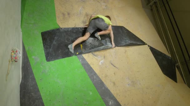 VERTIKAI: Fiatalember mászik fel mesterséges fal segítségével csak fekete kötet tartja. — Stock videók