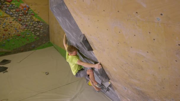 FECHAR UP: Tiro de ação de um alpinista do sexo masculino pulando para cima para alcançar um volume preto segurar. — Vídeo de Stock