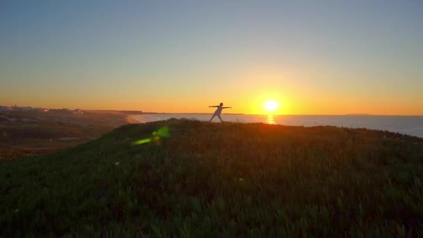 Gün batımında plajda yoga yapan zinde bir kadın üçgen pozu veriyor.. — Stok video