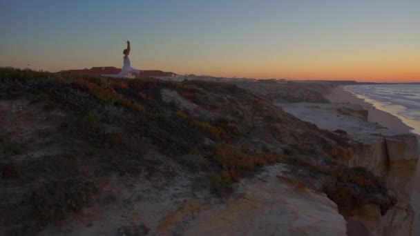 DRONE: Cinematic shot of a woman performing yoga on top of a cliff facing ocean. — Stock Video
