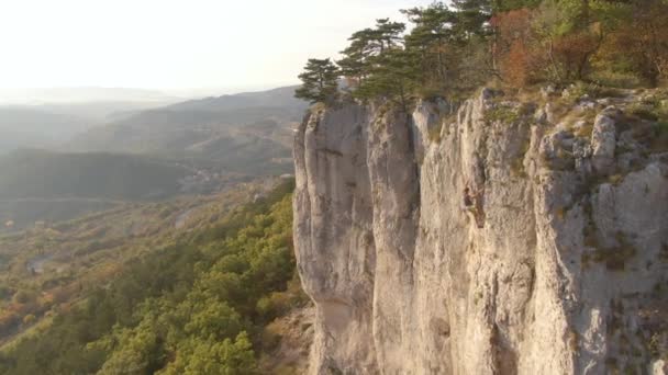 Látványos felvétel egy férfi hegymászóról, aki egy szikla tetejére tart. — Stock videók