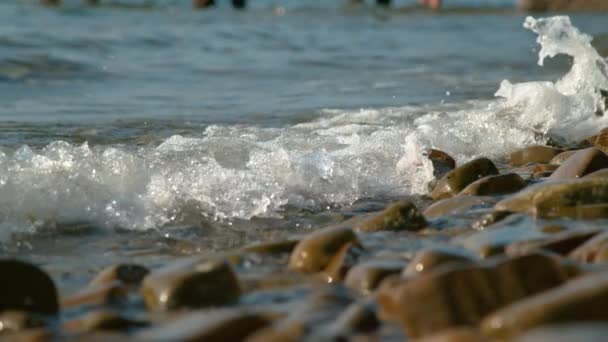 CERRAR: Pequeña ola de espuma del océano barre la playa de guijarros de color marrón. — Vídeos de Stock