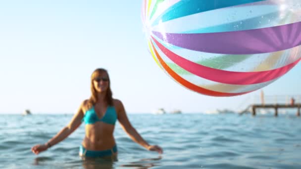 CHIUSURA: Donna allegra in bikini osserva la palla gonfiabile cadere in mare — Video Stock