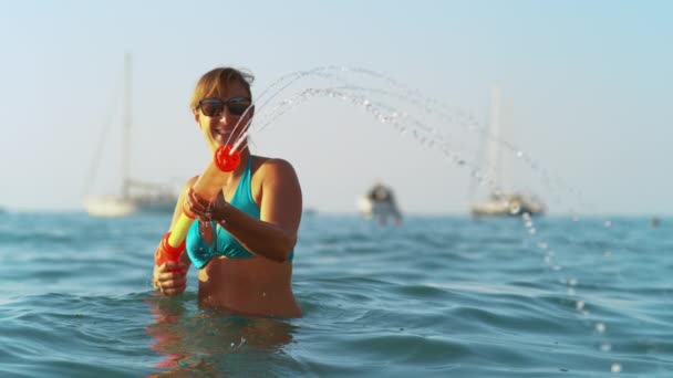 COPY SPACE: Cheerful woman plays with a squirt gun during her summer vacation. — Stock Video