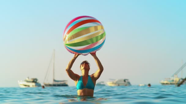 CLOSE UP: молодая женщина в бикини играет в солнечный вечер с огромным надувным мячом — стоковое видео