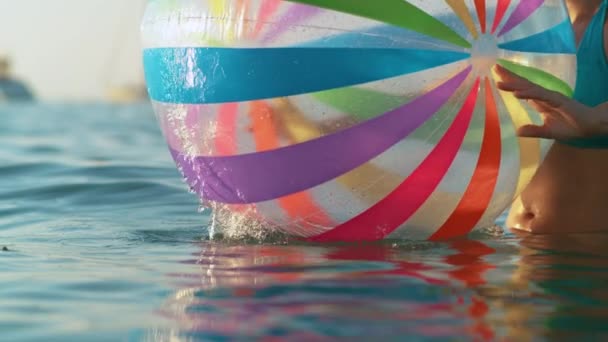 CERRAR: Mujer en bikini hace girar una pelota inflable sobre la superficie del mar — Vídeos de Stock