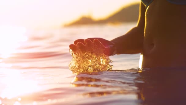 LENS FLARE: Raios de sol dourados à noite brilham sobre a jovem mulher salpicando água do oceano. — Vídeo de Stock