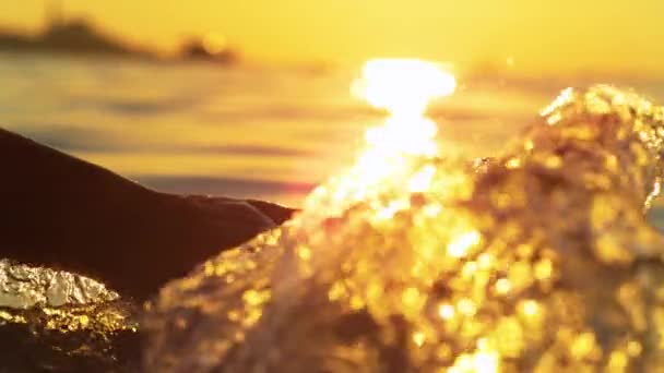 CHIUDI: Giovane donna spruzza acqua trascinando la mano lungo la superficie del mare. — Video Stock