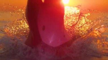 Altın gün doğumu, ilk olarak denize dalan genç kadının üzerinde parlıyor..