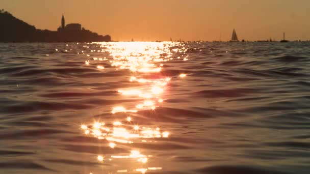 FLARE DE LA LENTE: El mar Adriático cerca de Piran brilla con el sol dorado de la noche de verano — Vídeos de Stock