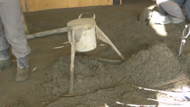 CLOSE UP: Workers spread wet cement across the ground of an unfinished house. — Stock Video