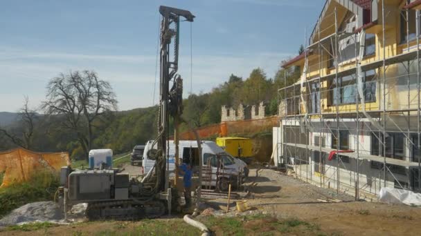 Dwóch wykonawców nadzoruje wiercenie otworu w ziemi dla pompy geotermalnej. — Wideo stockowe