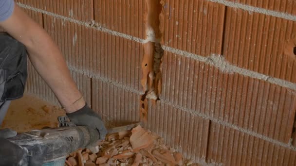 İşçi, kurulum sırasında tuğla duvarı kırmak için kaya matkabı kullanıyor — Stok video