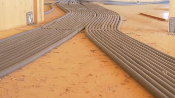 CLOSE UP: Grey corrugated tubing runs along the wooden floor of unfinished house — Vídeo de stock