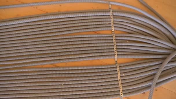 ARRIBA: Tubo corrugado gris corre a lo largo del piso de madera de la casa sin terminar — Vídeo de stock