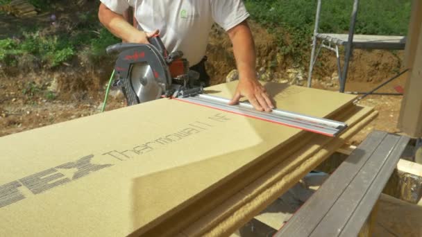 CLOSE UP: Contractor uses a handheld circular saw to cut sheets of insulation. — Stock Video