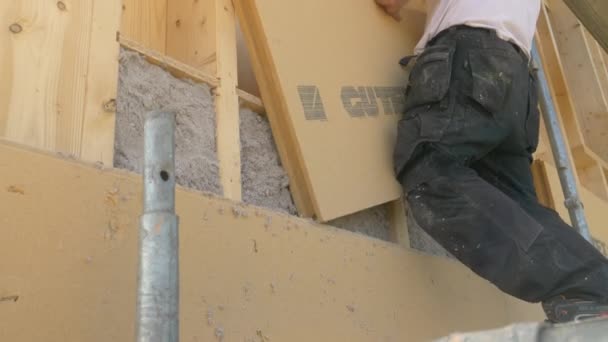 CLOSE UP: Entreprenören lägger isoleringspaneler på en vägg fylld med cellulosa. — Stockvideo