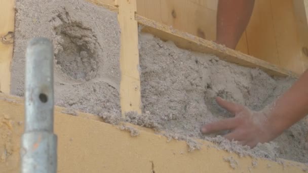 CLOSE UP: Unrecognizable man manually adjusts cellulose blown into wood wall. — Vídeos de Stock