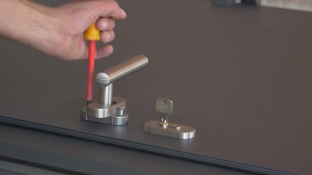 CLOSE UP: Locksmith fastens screws while mounting a handle on the front door. — Vídeo de stock