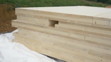 İnşaat alanında bir yığın CLT duvar paneli açıkta duruyor..