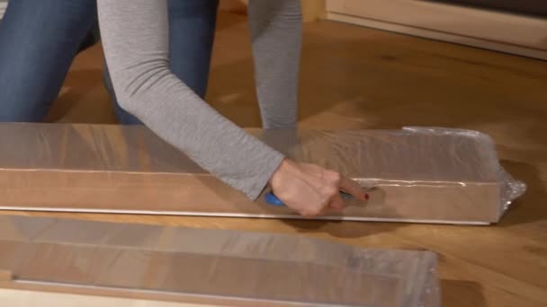CERRAR: Mujer irreconocible utiliza un cortador de caja para desempaquetar piezas de muebles. — Vídeos de Stock