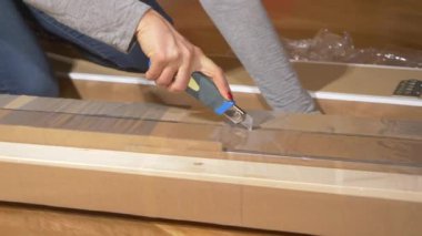 Kadın, bir parça mobilyanın plastik folyosunu keser ve soyar..