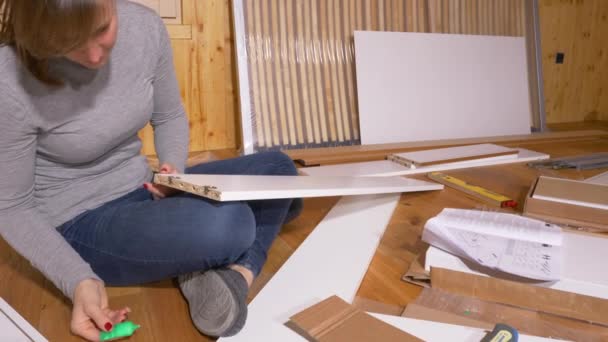 CERRAR: Las hembras pegan pequeñas clavijas de madera en el tablero mientras ensamblan muebles. — Vídeo de stock